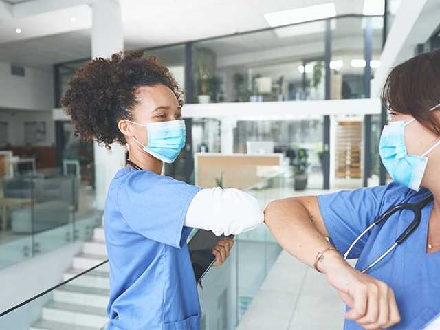 two nurses bumping elbows