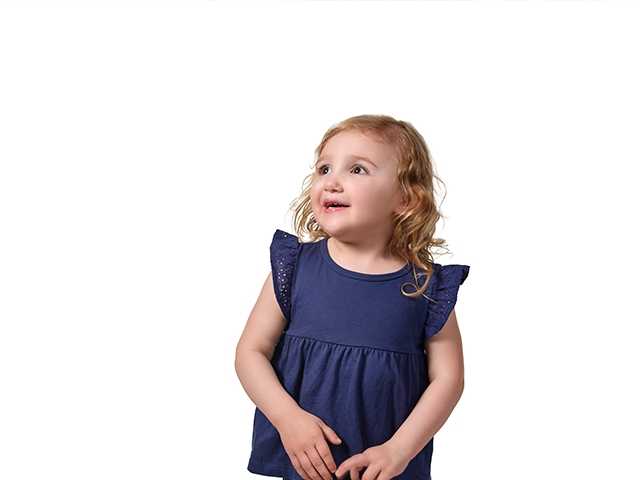 Young girl in dark blue shirt and jeans, arms and hands at her sides, looking up into the distance