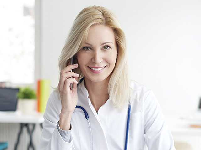 Female provider on cell phone, smiling for photograph.