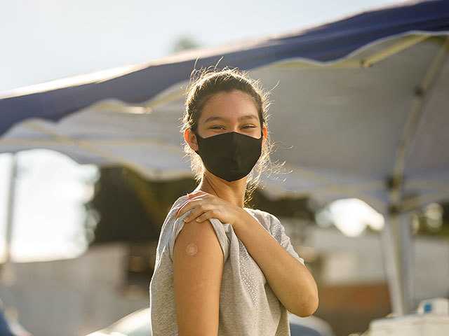 Girl showing upper arm with small bandage.