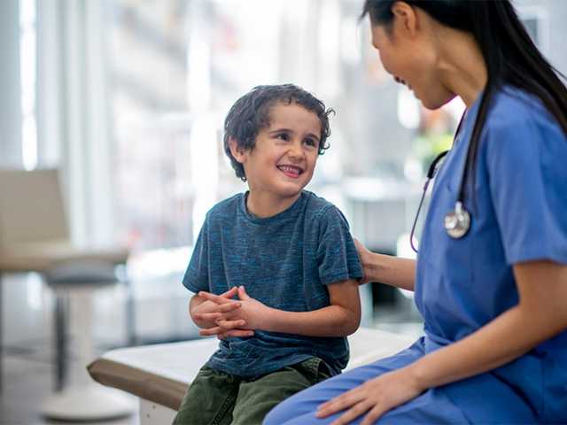 Healthcare provider talking with young boy.