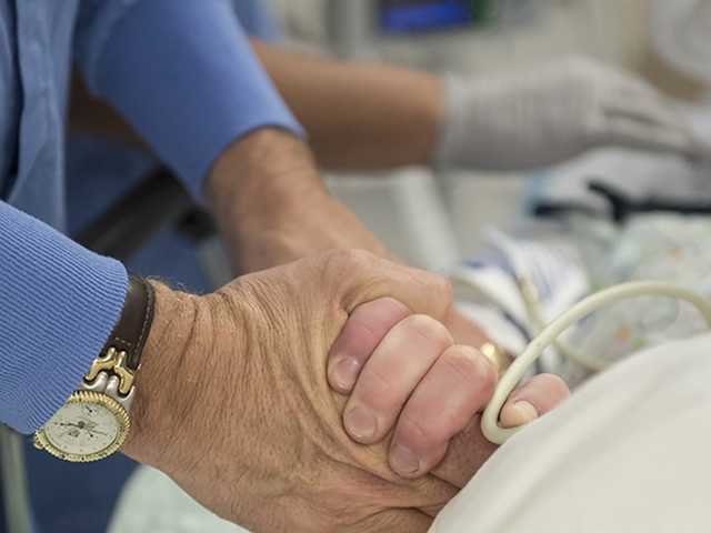Man holding a patients hand.