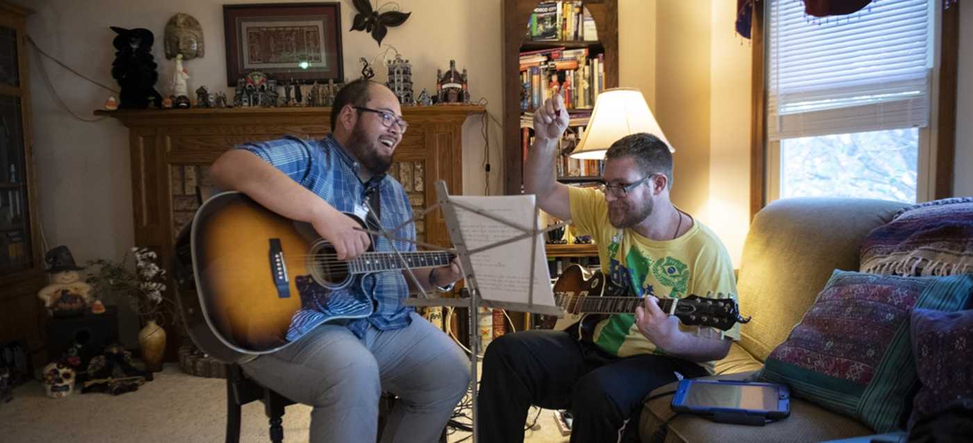 Two people playing guitar together at an indoor location