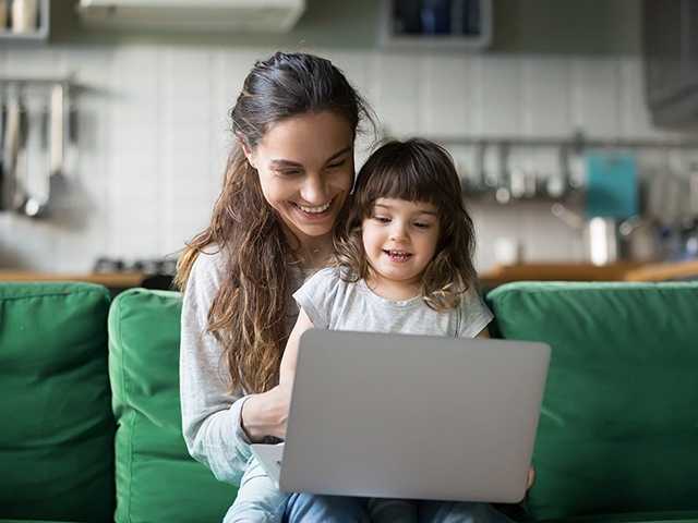 Woman sitting with child in front of laptop.
